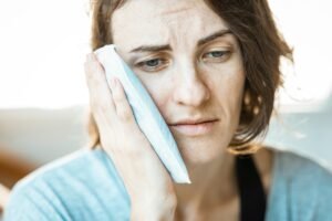 woman applying ice on her jaw
